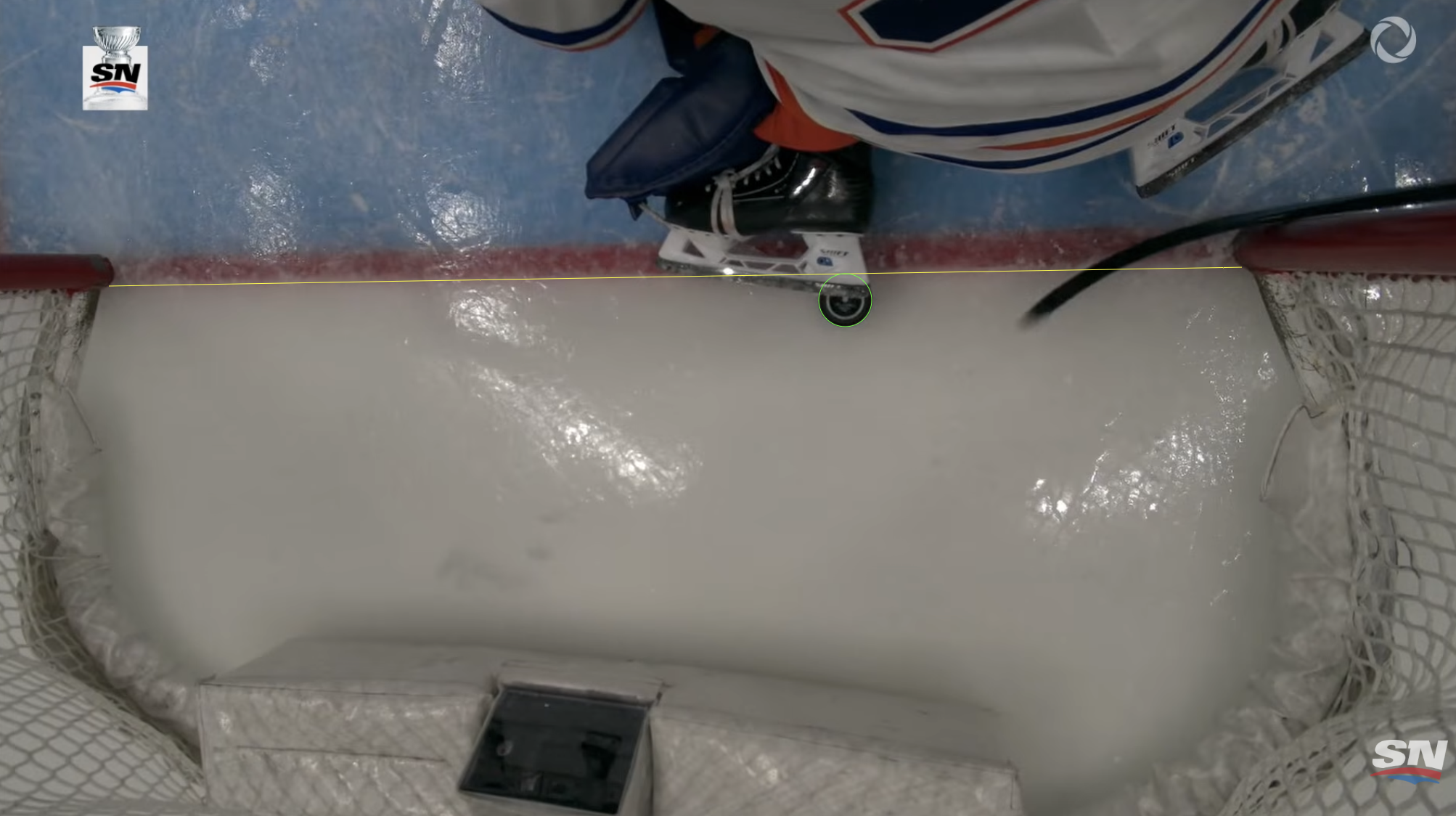 Overhead broadcast frame with the goal line highlighted in yellow and the puck circled in green